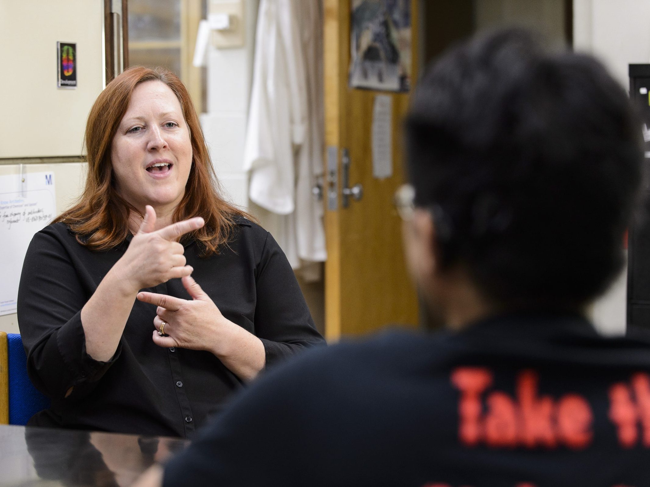A woman using sign language to communicate with a man in front of her.