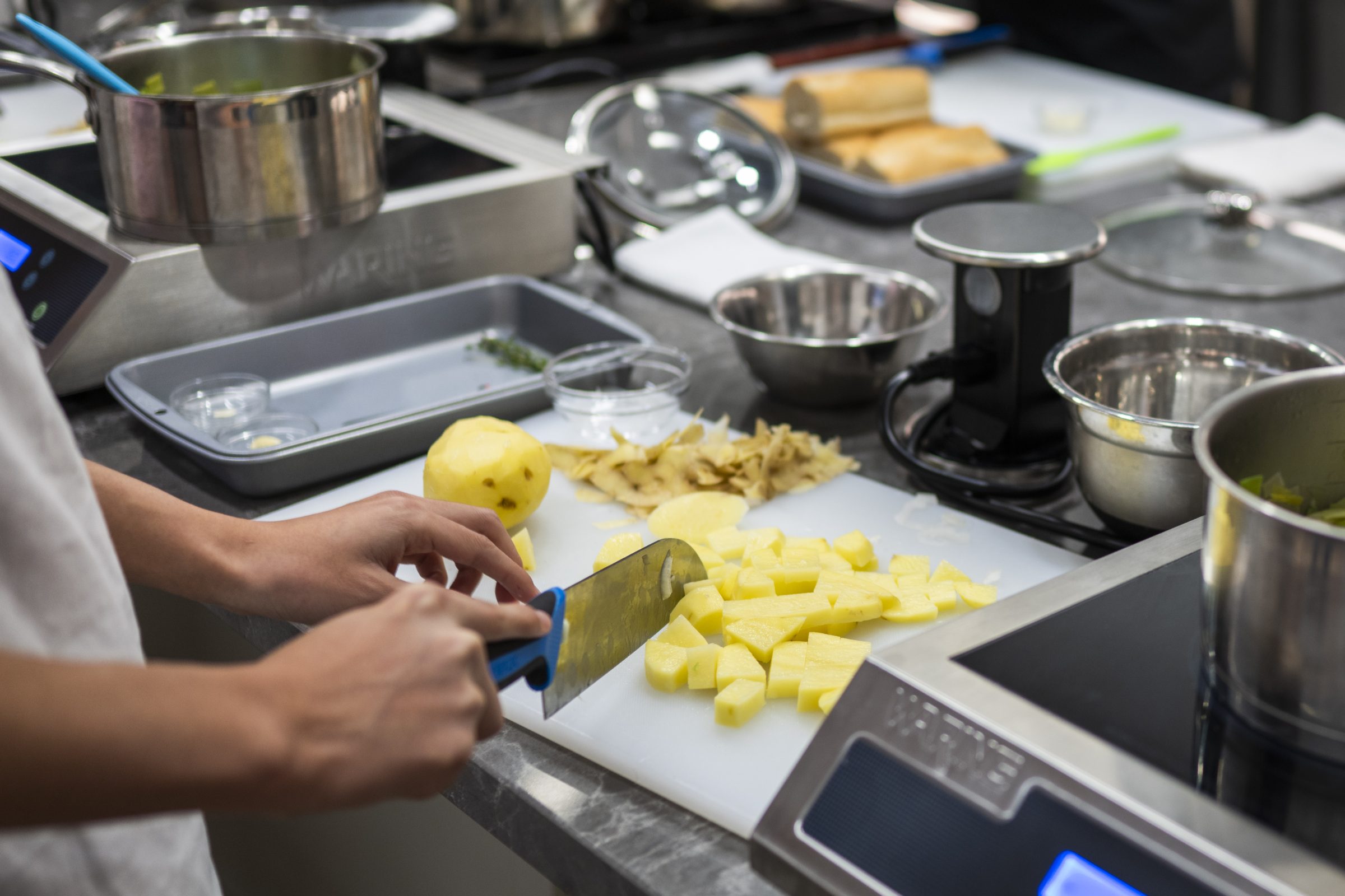 Someone cutting potatoes into small pieces in a kitchen.