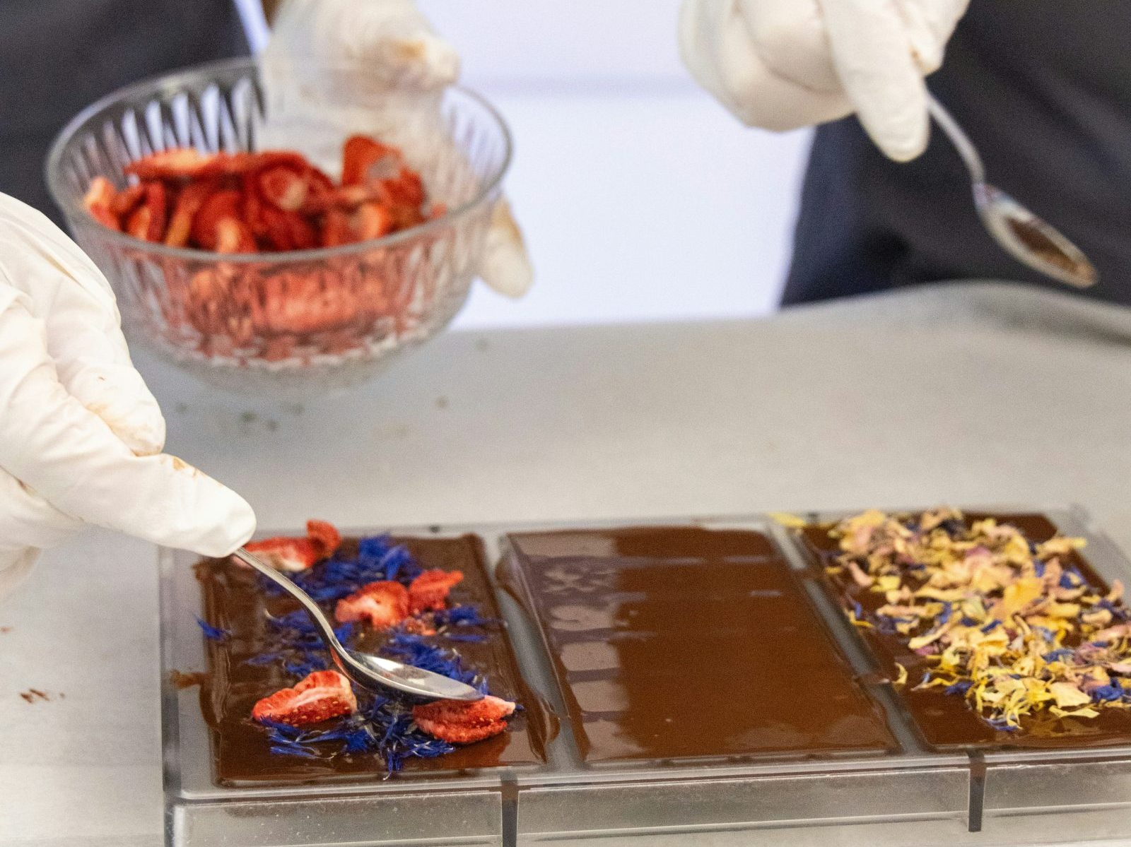 Adding toppings to a chocolate bar in a mold