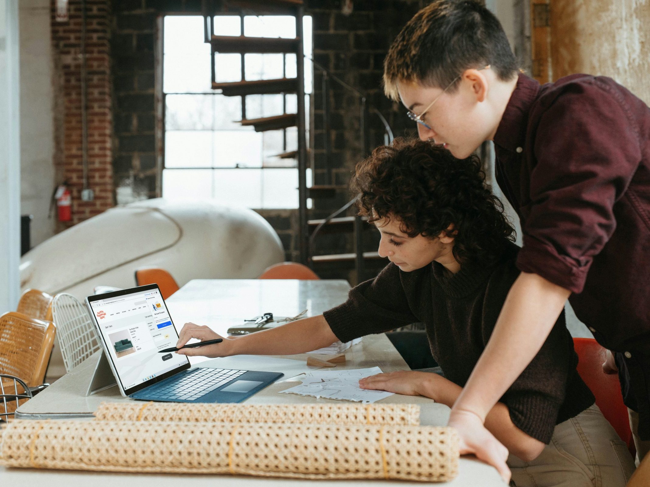 Two people overlooking a laptop in a business setting.