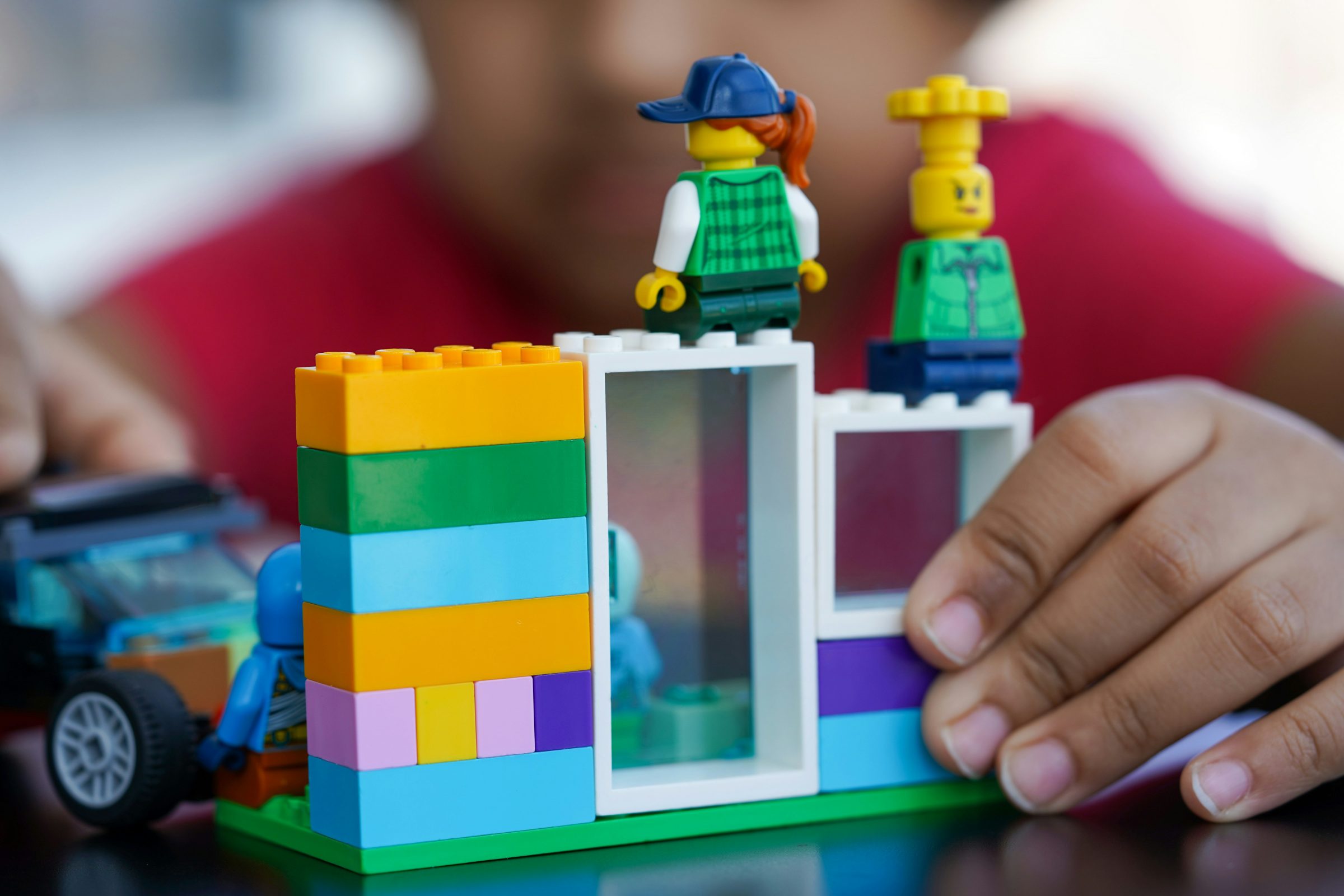 Photo by Ravi Ralwe
Small child playing with LEGO. Start to a house with a door and window, there are two LEGO mini figurines on top.