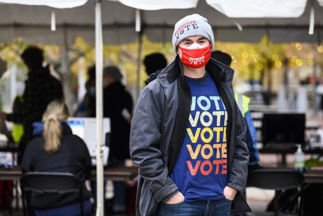 Man in a mask wearing a Vote shirt