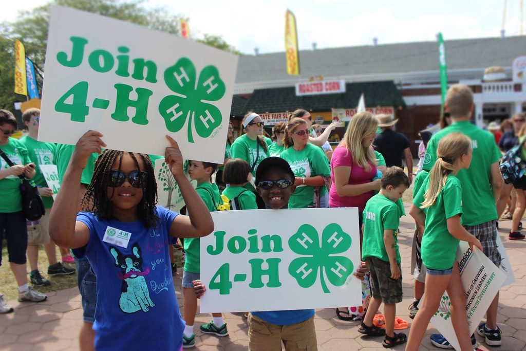 Two young kids holding signs that say "Join 4-H"