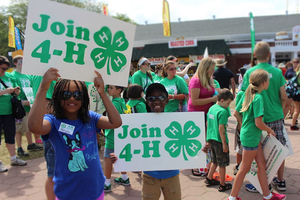 Two young kids holding "Join 4-H" signs