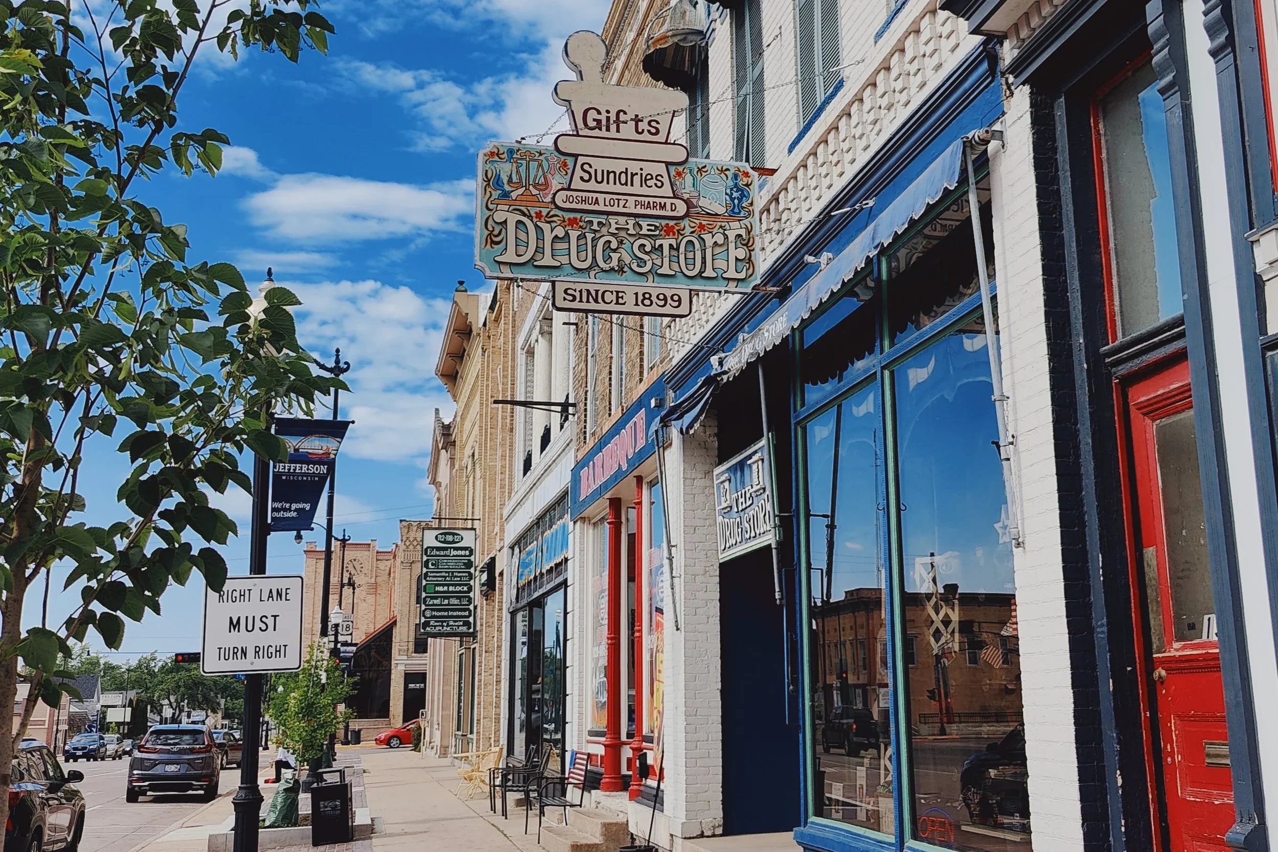 Downtown storefronts specifically showing the sign for Sundries The Drug Store. 