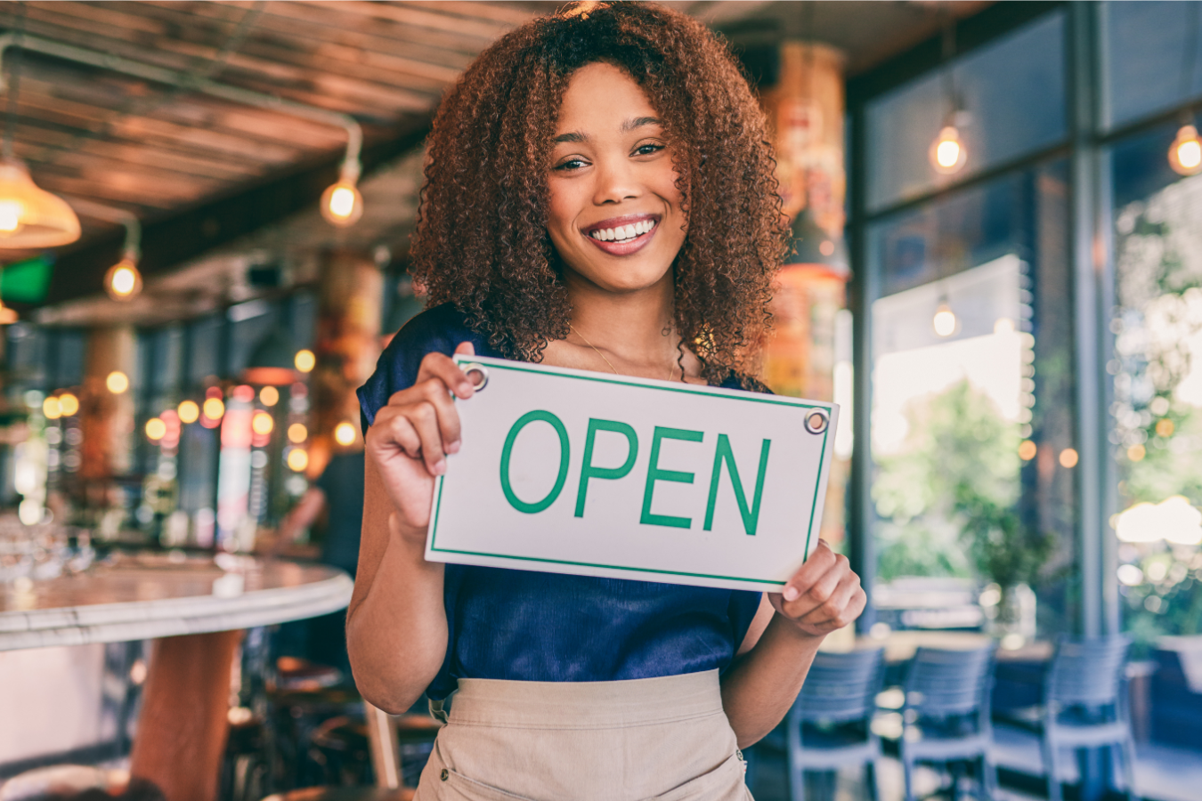 A woman holding an, "OPEN" sign.